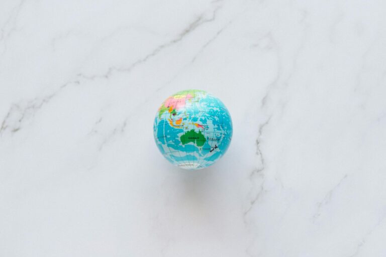 A small, colorful globe rests on a marble surface, symbolizing global exploration and travel planning.